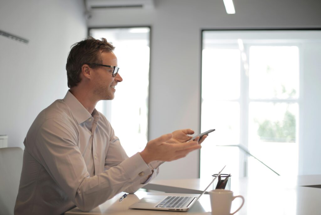 Confident businessman engaging in a discussion with a smartphone in a contemporary office setting.